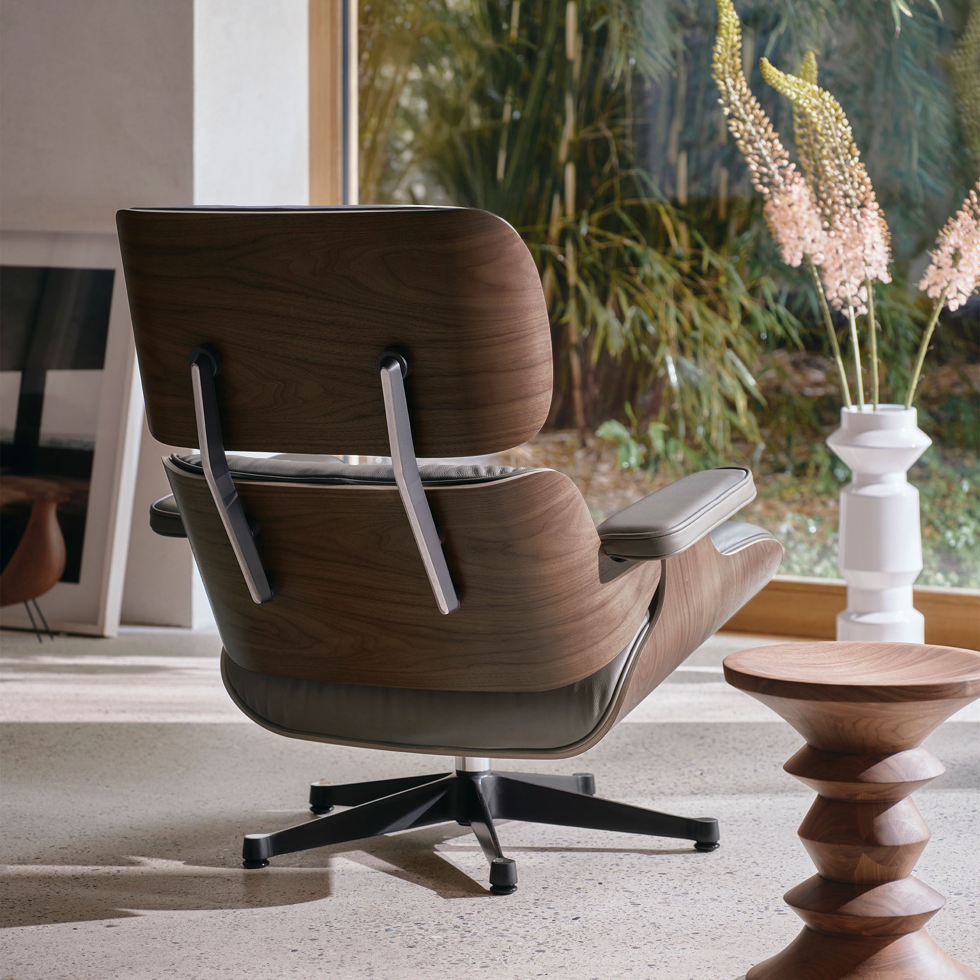 Eames Lounge Chair cu Otoman, lemn de nuc băițuit și bază satinată cu laterale negre